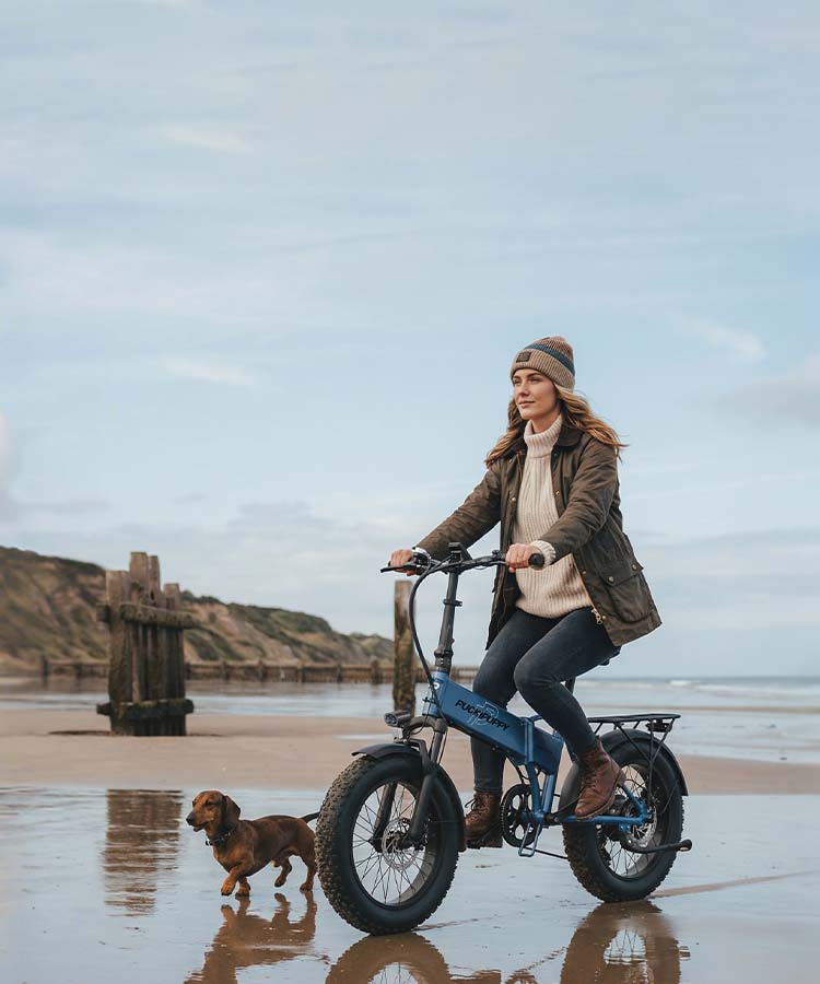 An enthusiast rides a blue PUCKIPUPPY Dachshund bike, pedaling steadily with a calm, relaxed expression.